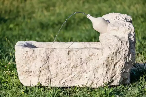 Bottiglia di Prosecco scolpita a mano in pietra su una fontana da giardino